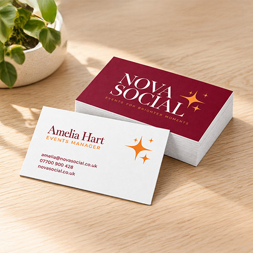 Straight corner business cards showing burgundy Nova Social branding and a white contact details reverse on a wooden desk.