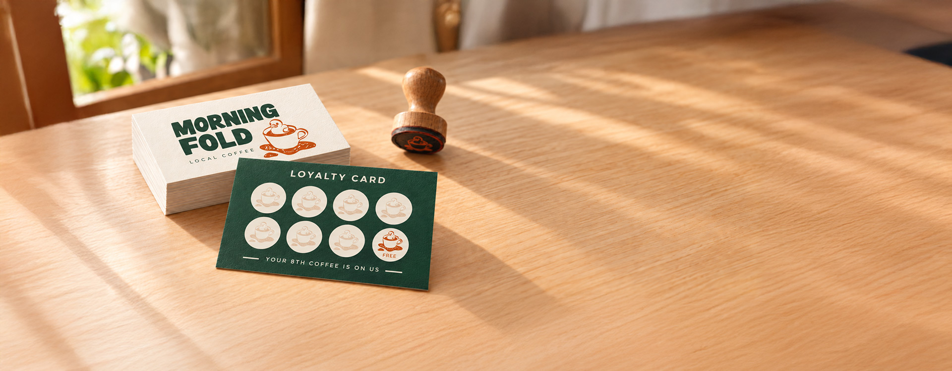 Morning Fold café loyalty cards with square corners, showing both sides beside a wooden stamp on a café counter.